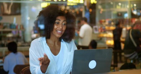 Charming multi-ethnic woman with afro hairstyle, sitting at laptop and talking while a video call. Online communication across the distance. Video conference. Online chat concept