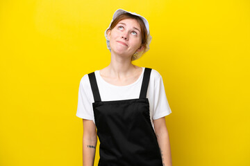 Young English fisherwoman isolated on yellow background and looking up