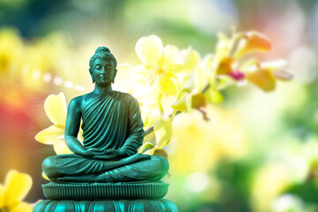 Buddha statue meditating on a natural blurred bokeh background.