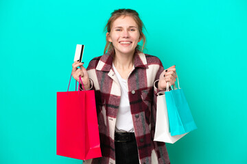 Young English woman isolated on blue background holding shopping bags and surprised