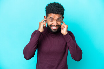 Young Brazilian man isolated on blue background frustrated and covering ears