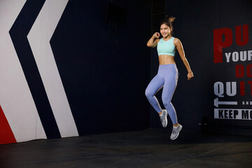 athletic young woman jumping up and training in the gym