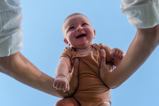 Hands Of Parent Picking Up A Happy Baby