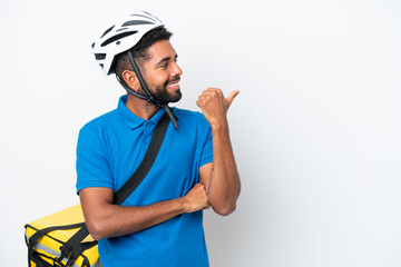 Young Brazilian man with thermal backpack isolated on white background pointing to the side to present a product