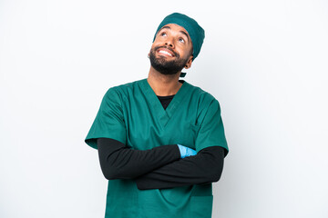 Surgeon Brazilian man in green uniform isolated on white background looking up while smiling