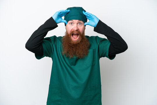 Surgeon redhead man in green uniform isolated on white background with surprise expression