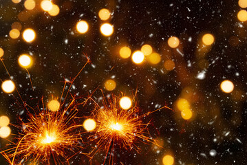 Fototapeta na wymiar Burning sparklers on abstract snowy background, party concept