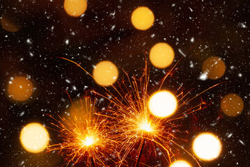 Burning sparklers on abstract snowy background, party concept