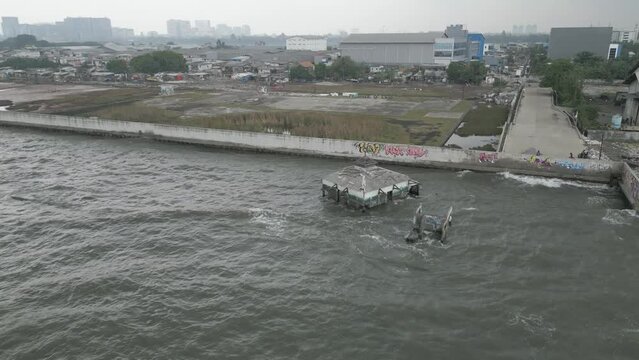 Jakarta, Indonesia - December 25, 2022: The Wal Adhuna Mosque is submerged in sea water behind a giant wall that was built to prevent sea water from entering the mainland due to rising sea levels.