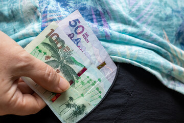 A woman takes out of her pocket one hundred and fifty pesos Colombian bills, South American money