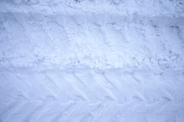 Traces of large tractor wheels in the snow. The imprint of the tread of municipal equipment during snow removal. Snowy, sunny.