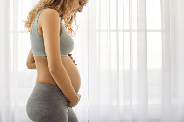Crop of healthy sporty young pregnant woman in sportswear touch big belly await for newborn baby birth. Happy future mom enjoy pregnancy follow healthy lifestyle. Motherhood concept.