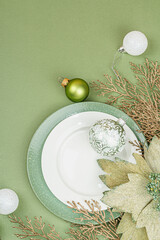 Christmas table setting with ceramic plates, traditional decor on Savannah Green color background