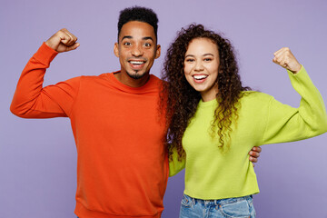 Fototapeta na wymiar Young couple two friend family man woman of African American ethnicity in casual clothes together show hand biceps muscles demonstrate strength power isolated on pastel plain light purple background