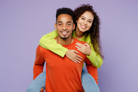 Young fun couple two friends family man woman of African American ethnicity wear casual clothes together giving piggyback ride to joyful, sit on back isolated on pastel plain light purple background.