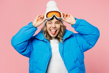 Snowboarder fun woman wear blue suit hat ski padded jacket hold take off goggles mask show tongue...