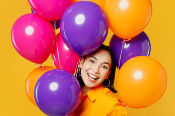 Fototapeta na wymiar Close up happy fun cute cheerful young woman wear casual clothes celebrating hold bunch of colorful air balloons look camera isolated on plain yellow background. Birthday 8 14 holiday party concept.