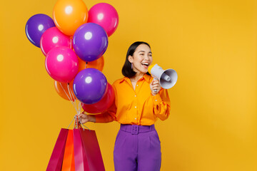 Young woman wear casual clothes celebrating hold balloons shopping package bags scream in megaphone...