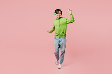 Full body young man of Asian ethnicity wear green hoody headphones listen to music dance laugh have...