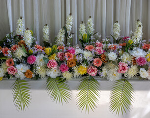 Close-up view of rows of white bouquets, roses and chrysanthemums of various colors.