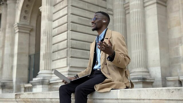 A handsome young African American man walks around the city, smiles and reads the news.