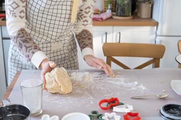 Hands knead thick dough on the kitchen table, decorated with festive decorations for Christmas and New year. Baking at home, aroma and comfort. Close-up