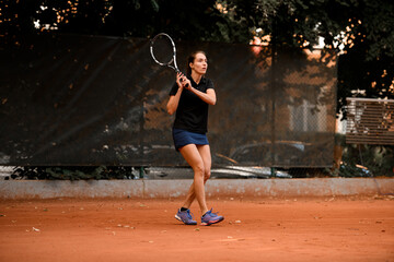 Active woman tennis player with racket ready to hit a tennis ball.