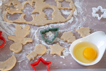 The hands of mom and daughter close-up cut out cookies from the dough with molds on a Christmas theme in the form of a snowman, a Christmas tree, stars