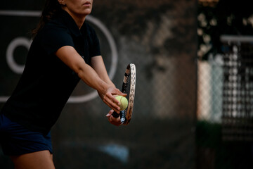 Selective focus on tennis ball and racket. Female tennis player prepares to serve during the match.