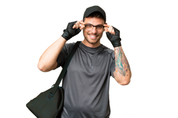 Young sport man with sport bag over isolated chroma key background with glasses and surprised