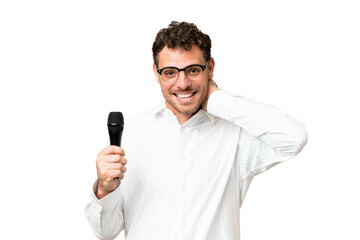 Brazilian man picking up a microphone over isolated chroma key background laughing