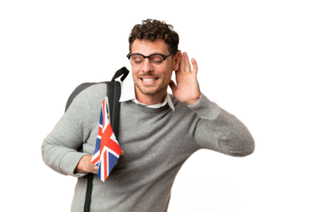 Brazilian man holding an United Kingdom flag over isolated chroma key background listening to something by putting hand on the ear