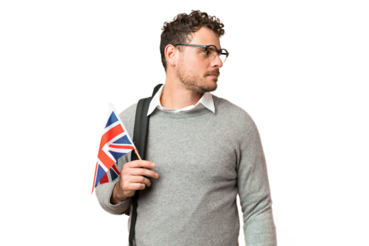 Brazilian man holding an United Kingdom flag over isolated chroma key background looking to the side