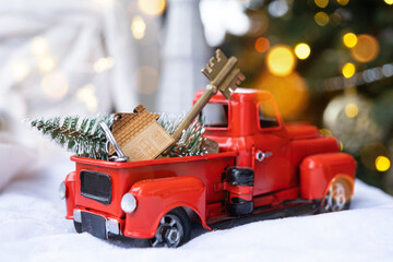 Red retro car with a Christmas tree decorates with the house key in the pickup truck for Christmas....