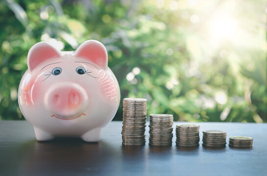 piggy bank with coin on old wooden table on bokeh blur background.concept of finance and investment