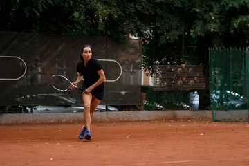 Fototapeta na wymiar Tennis training - woman player with tennis racket playing at outdoor tennis court.