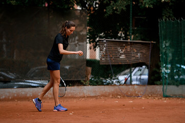 professional female tennis player holding ball and racket preparing to serve at beginning of game