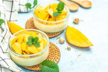 dessert panna cotta with pieces of fresh mango in glass jars on a light background. place for text, top view