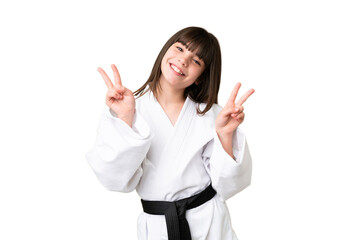 Little Caucasian girl doing karate over isolated background showing victory sign with both hands © luismolinero