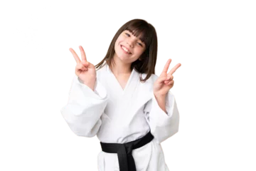 Foto op Canvas Little Caucasian girl doing karate over isolated background showing victory sign with both hands © luismolinero
