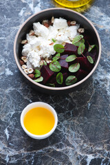 Bowl with beetroot and feta cheese salad, vertical shot on a black marble background, elevated view