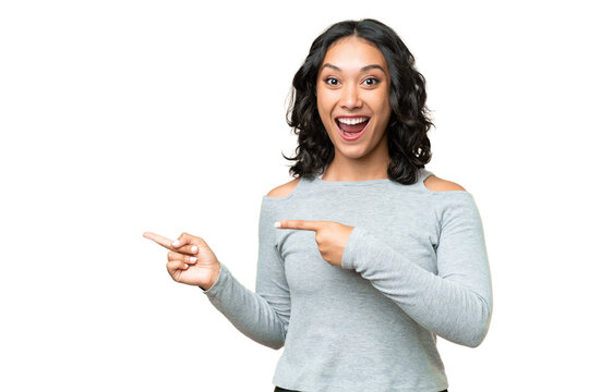 Young Argentinian woman over isolated background surprised and pointing side