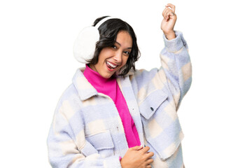 Young Argentinian woman wearing winter muffs over isolated background making guitar gesture