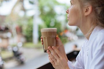 Girl drink latte coffee in street cafe in Bali