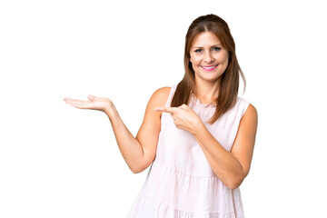 Middle age woman over isolated background holding copyspace imaginary on the palm to insert an ad