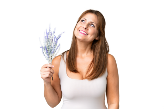 Middle age caucasian woman holding lavender over isolated background looking up while smiling