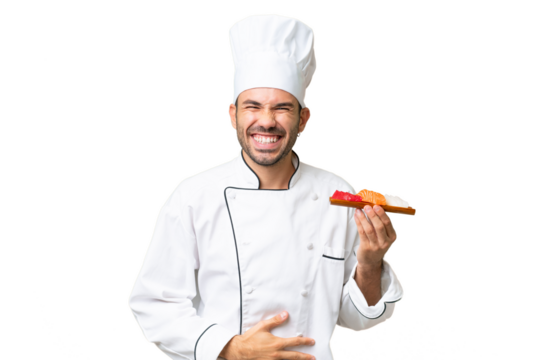 Young caucasian chef holding a sushi over isolated background smiling a lot