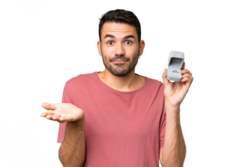 Young handsome caucasian man holding a engagement ring over isolated background making doubts gesture while lifting the shoulders