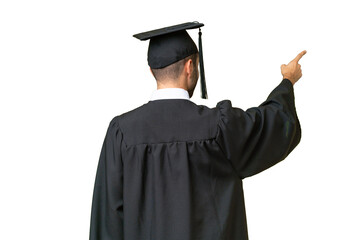 Young university graduate man over isolated background pointing back with the index finger