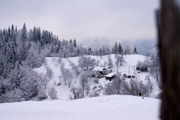 View from the top of the hill of the Ukrainian Carpathians to the settlement with houses covered with snow in winter